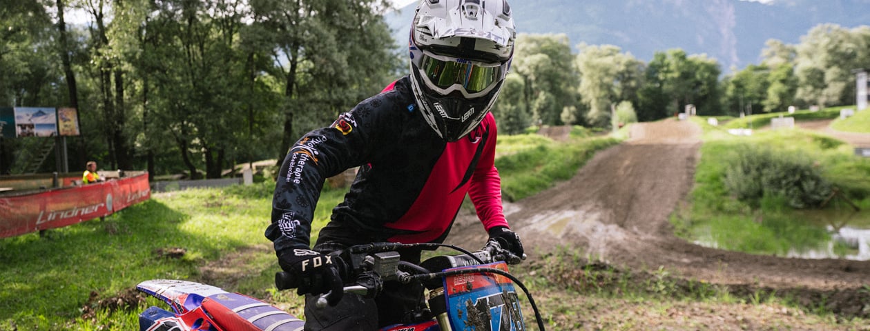 Ein Motorradfahrer trägt ein selbstgestaltetes Trikot von 'owayo' während eines Motocross-Wettbewerbs im Freien.