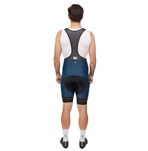 Back view of a man wearing a customized cycling bib shorts with a blue geometric pattern and black padded seat area, paired with a white sleeveless top featuring a black back panel.