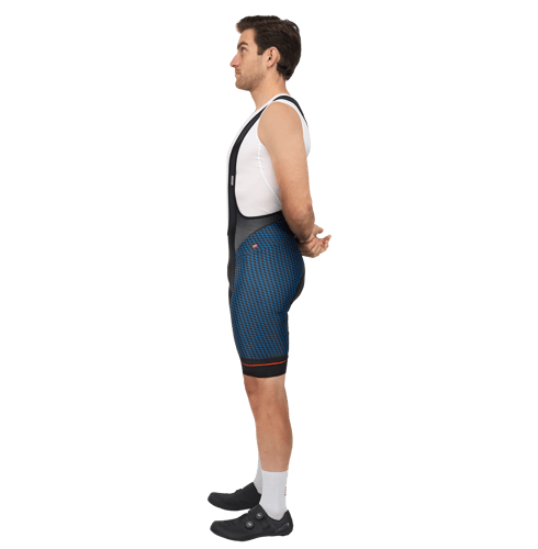 Side view of a man wearing blue and black patterned cycling shorts with a white top and black shoes.