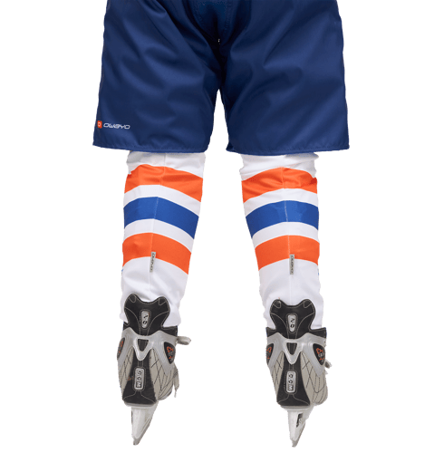 Vista trasera de un jugador de hockey sobre hielo con pantalones cortos azules con el logo 'owayo' y protectores de espinilla con rayas naranja, blanco y azul, combinados con patines de hockey sobre hielo.