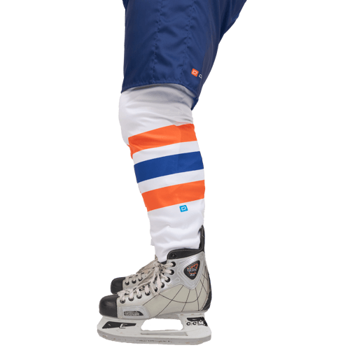 Vista lateral de un jugador de hockey sobre hielo con pantalones azules y calcetines blancos con rayas naranjas y azules, combinados con un patín de hockey sobre hielo.