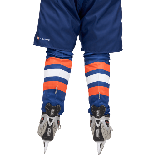 Back view of an ice hockey player wearing blue pants with the 'owayo' logo and striped shin guards in orange, white, and blue, worn over ice hockey skates.