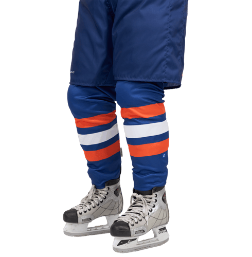 A model wearing blue hockey gear with orange and white stripes on the leg pads and hockey skates.
