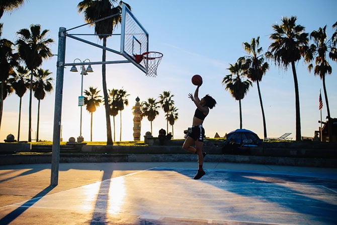 Woman doing a lay up with a basketball.