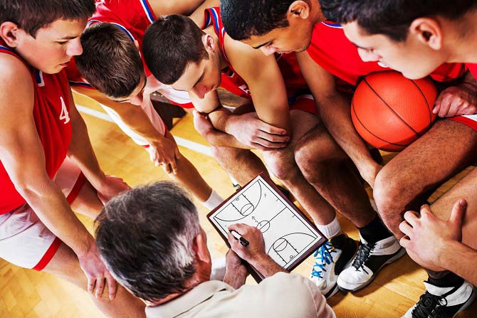 The next play is being discussed during a time out by the basketball coach.