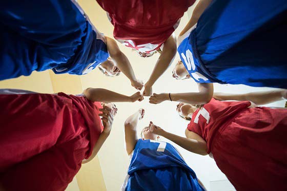 basketball team photgraphed from below, hands together in the middle