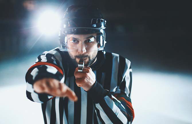Referee blows his whistle at a game of ice hockey