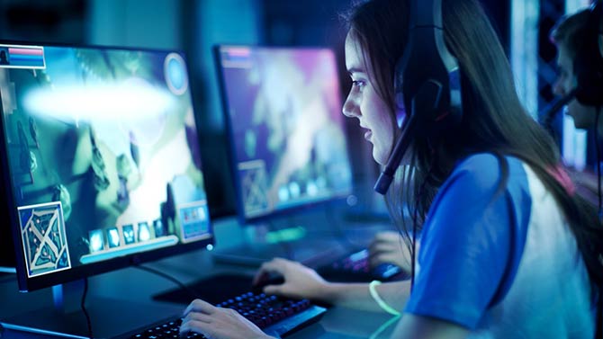 Jeune femme assise devant son ordinateur et jouant à des jeux esport