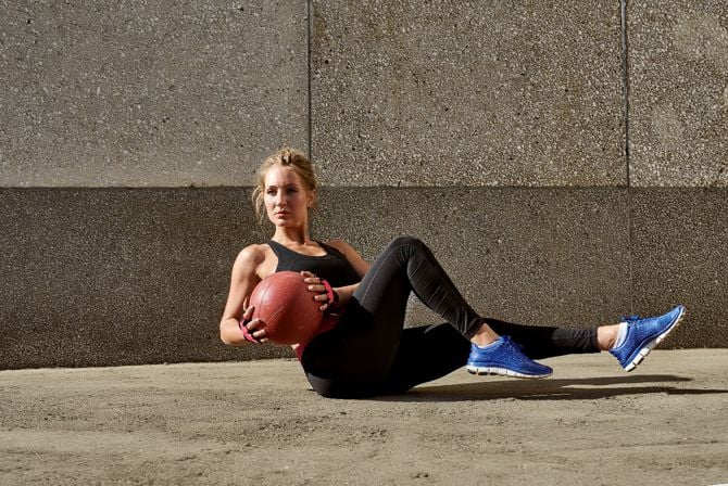 Eine Frau macht eine Fitnessübung mit einem Medizinball im Sitzen