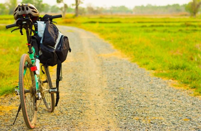 Bicycle with rucksack and helmet on gravel path