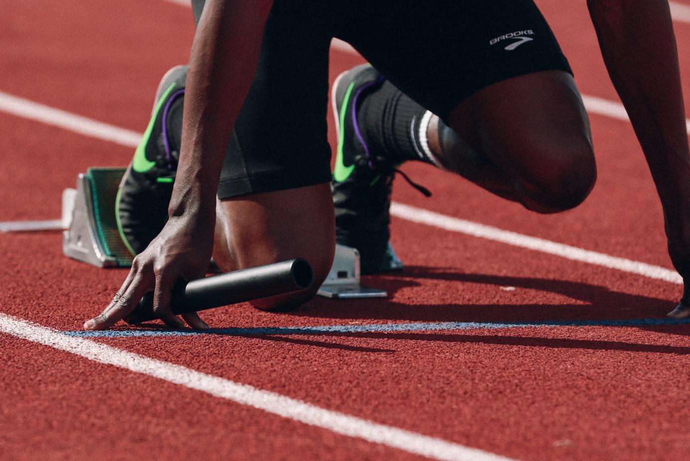 A relay runner settles into his starting blocks