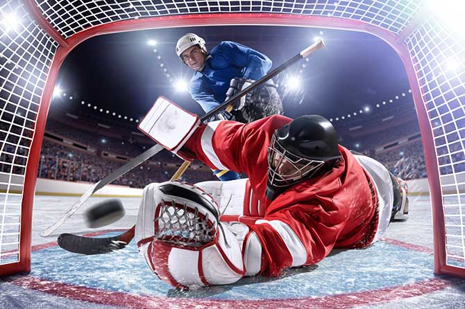 Ice hockey players shooting into the goal and goalie in the hockey goal