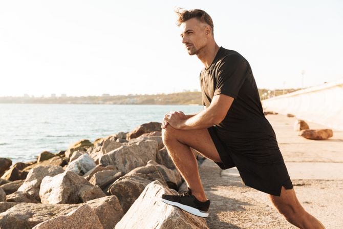 Jogger stretcht sich am Meer