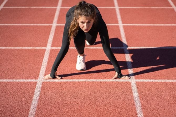 Sportlerin ist in Startposition auf Tartanbahn für Sprinttraining
