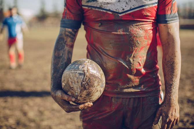 Athletes with dirty football in very muddy dirty jersey