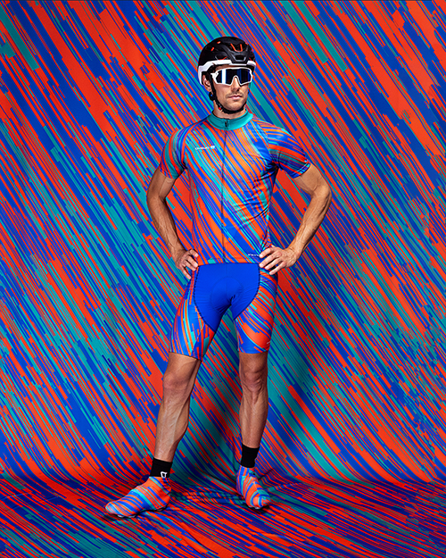 Een man draagt een kleurrijk gestreept sportoutfit met helm en zonnebril voor een abstracte achtergrond.