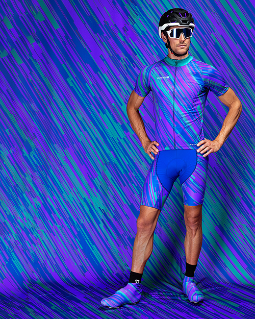 Een man draagt een kleurrijk gestreept sportoutfit met helm en zonnebril voor een abstracte achtergrond.