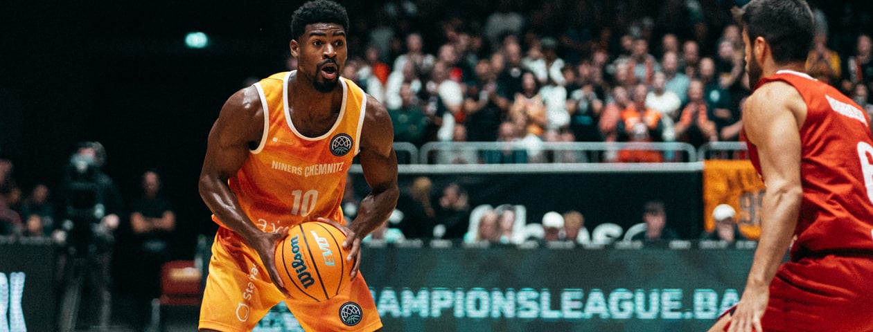 A basketball player in a yellow Owayo jersey dribbling while an opponent in a black jersey tries to defend him