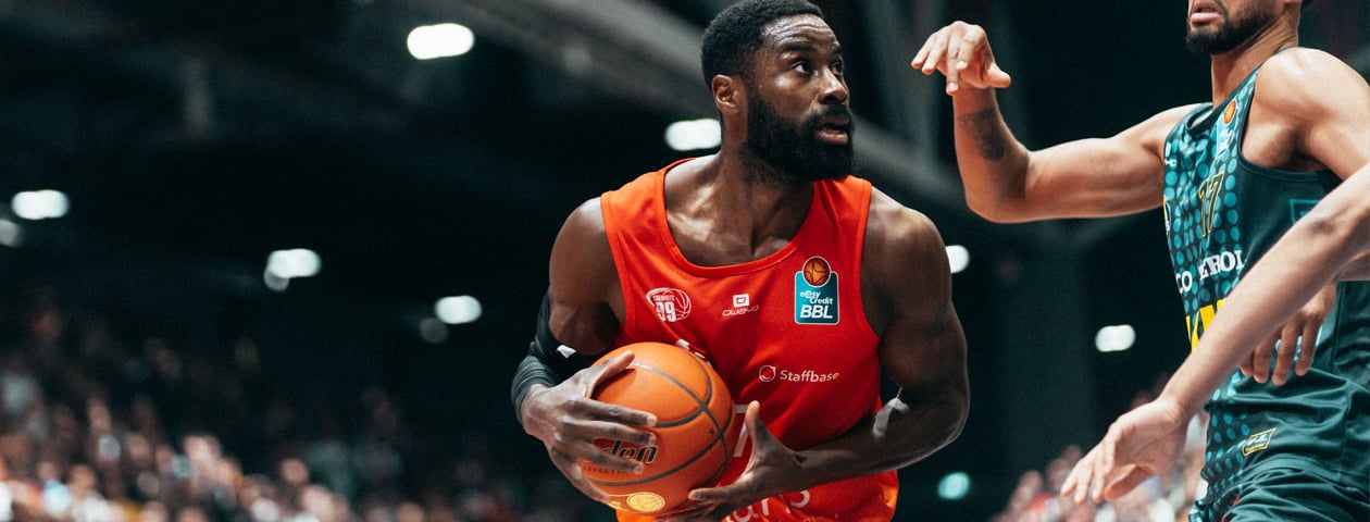 A basketball player in a yellow Owayo jersey dribbling while an opponent in a black jersey tries to defend him