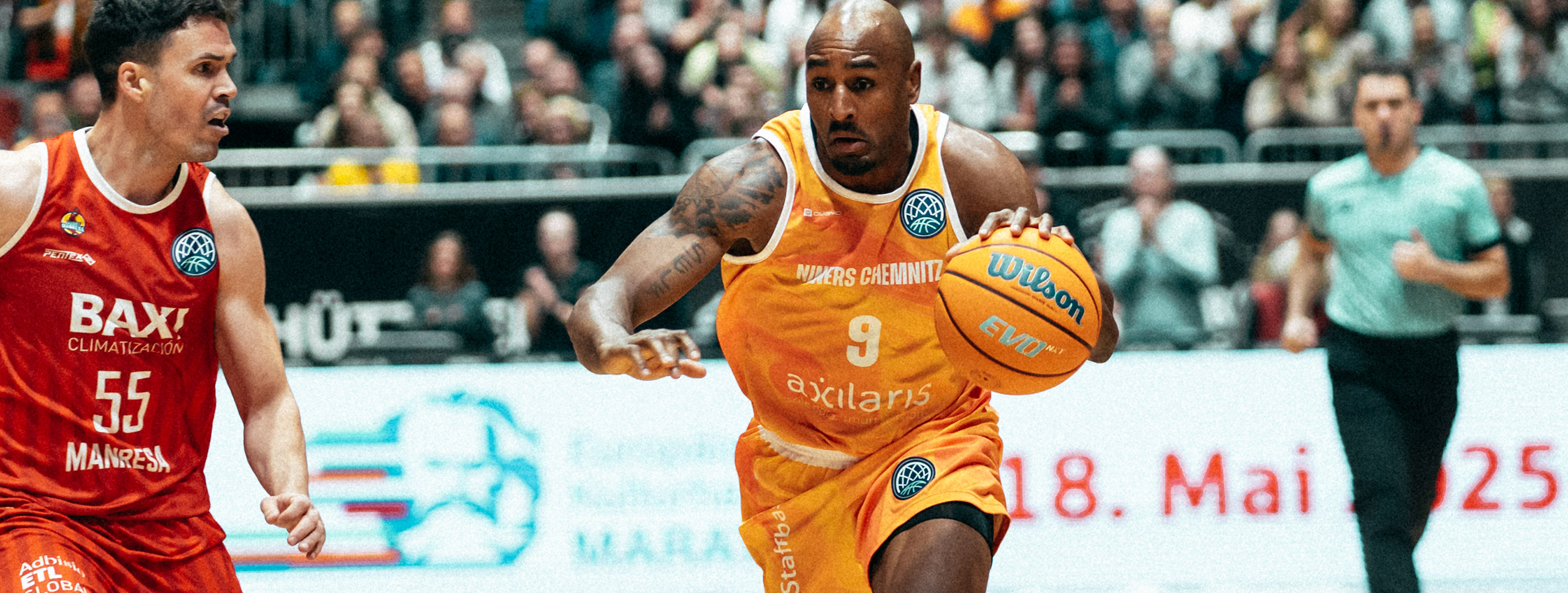 A basketball player in a yellow Owayo jersey dribbling while an opponent in a black jersey tries to defend him