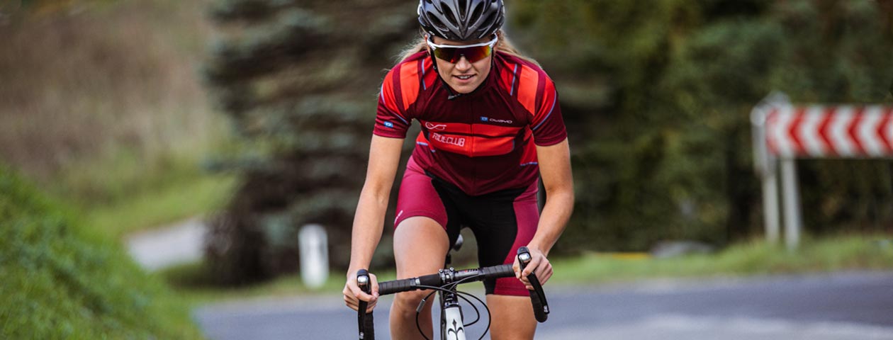 Woman in an individualised cycling jersey on her bike