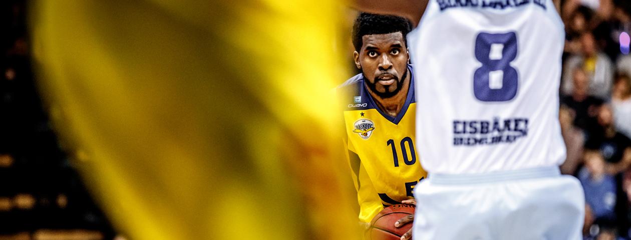 Basketballspelers van de Eisbären Bremerhaven en de EWE Baskets Oldenburg in duel in een zelf ontworpen blauwe basketbalshirt